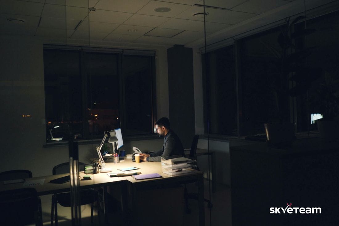 lonely at work, a man sitting at his desk, it's dark outside
