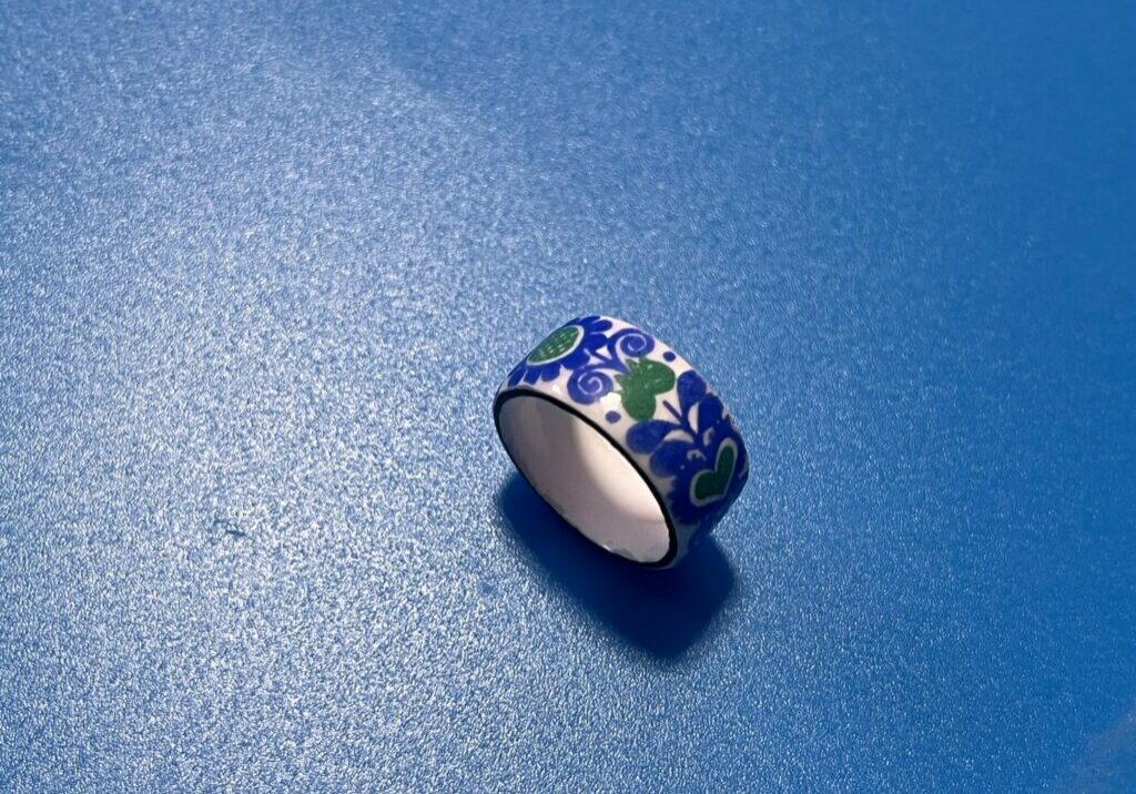 photo of a small enamel ring that is blue and green flowers on a blue background