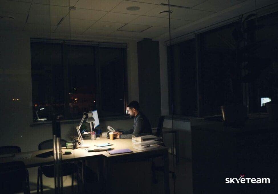 lonely at work, a man sitting at his desk, it's dark outside