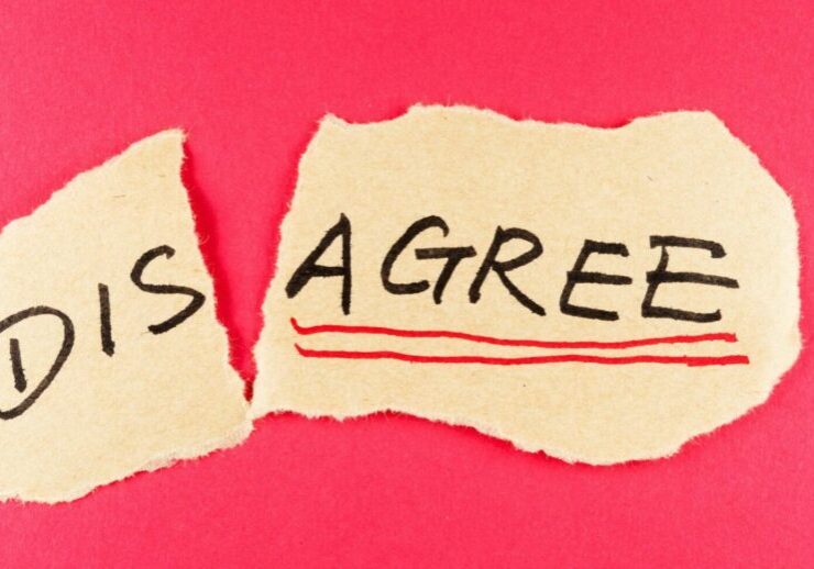 the word disagree written on a piece of yellow paper that is torn into two parts. dis and agree maintaining professional relationships